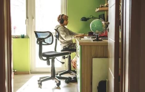 boy in his bedroom sitting at a desk on the computer
