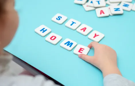 Girl spells out the words "Stay Home" with tiles