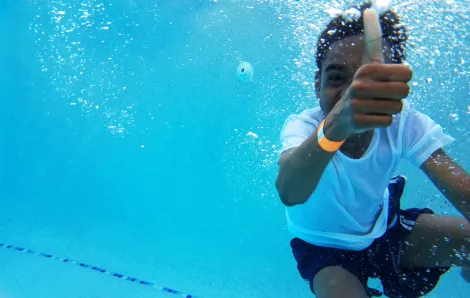 boy underwater in the pool giving a thumbs up