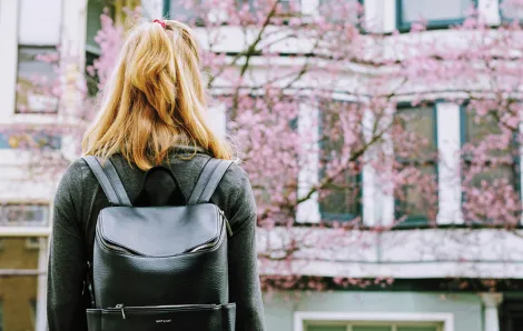 girl wearing a backpack looking up at a college building