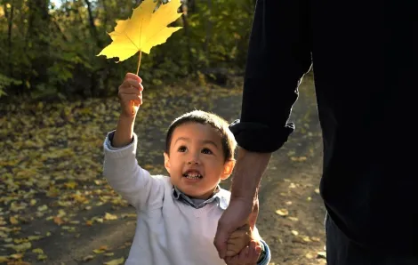 Boy holding autumn leaf with light on his face best family photo tips