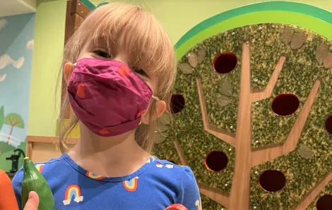 Happy young girl wearing a face covering at KidsQuest Children's Museum in Belleuve reopening after pandemic closure