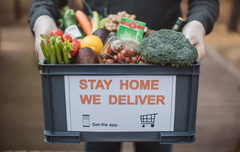 plastic crate full of food with the words 'stay home we deliver' on the front