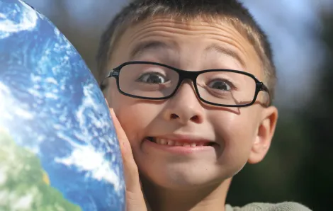 Cute boy with glasses holding up a globe