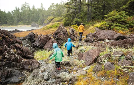 family hiking over rocks with evergreen trees around