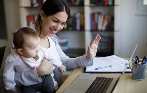 New mother with her baby joining a video conference on a laptop