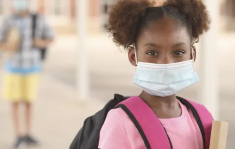 Young girl wearing a surgical mask and a school backpack