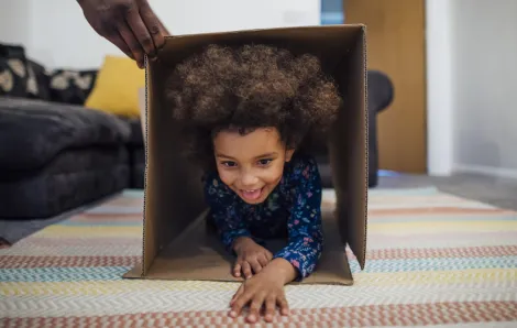 a child crawls through a cardboard box, part of an indoor obstacle course challenge