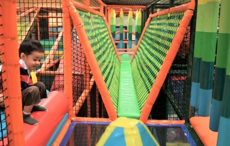 Small boy crouching in large colorful climbing structure at indoor play gym Safari inside Seattle's Southcenter Mall