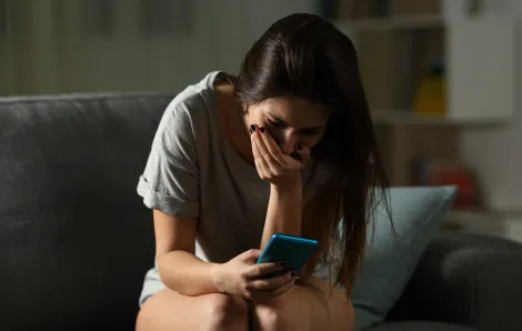 Upset teen girl receiving bad news online on her cell phone
