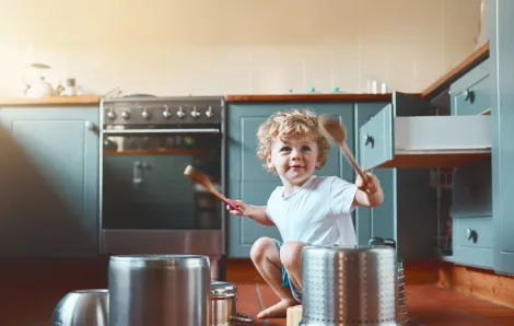 Portrait of an adorable little boy playing with pots in the kitchen