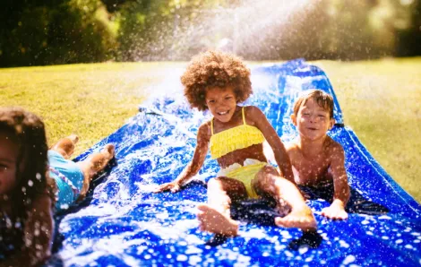 Kids play on a slip n slide, an epic outdoor toy to pull out in summer