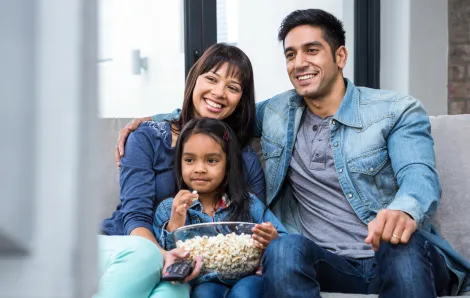 family sitting on a couch with popcorn and a remote