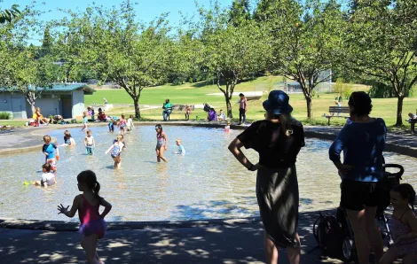 Families enjoying the wading pool at Seattle's Dahl Playfield. Wading pools open for summer June 26
