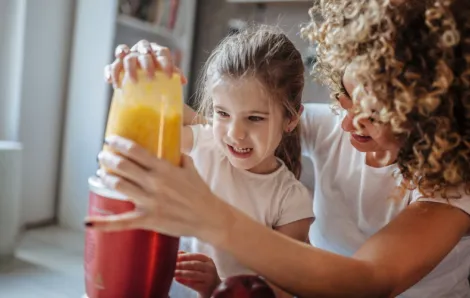 Kid-making-smoothie-with-mom