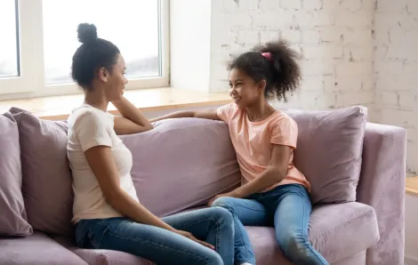 mother talking to her preteen daughter on a couch