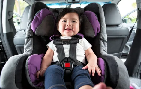 Cute growing baby in rear-facing car seat with family headed to Target car seat trade-in recycling event
