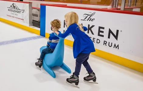 Two kids, one riding and one pushing, test out Bobby the Seal skate aid at new Kraken community Iceplex in Seattle