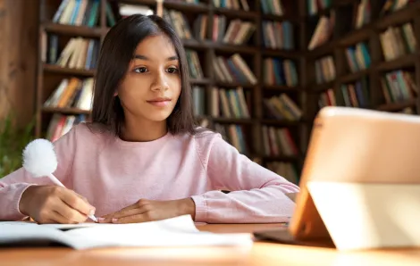 Young girl sits at a desk working on her homework