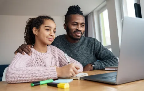 father and daughter sitting on a laptop together