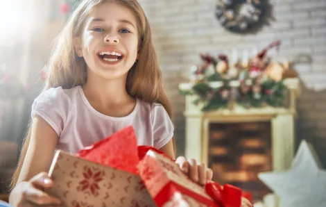 girl opening a gift with a fireplace in the background