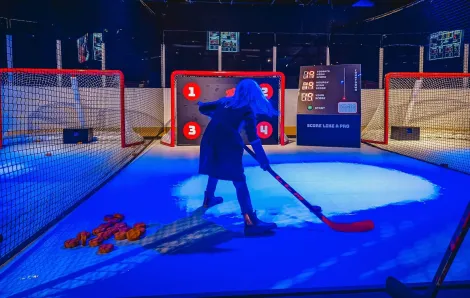 A young girl visiting an exhibit called Hockey Faster Than Ever at Seattle's Pacific Science Center shoots a goal at an interactive station