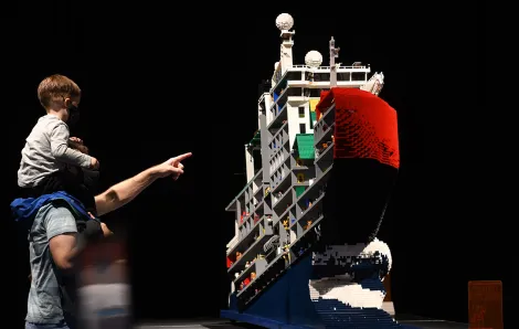 Dad with child on his shoulders point and look at huge Lego model of an ice breaker ship at Seattle's Awesome Lego interactive exhibit at seattle center's fisher pavilion