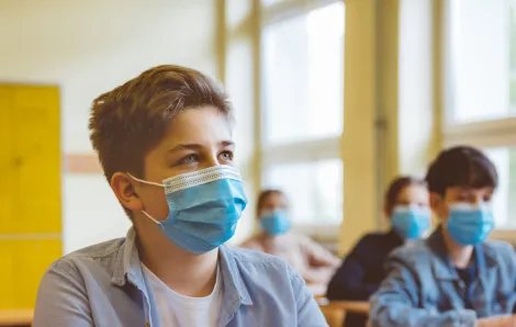 High school students wearing N95 face masks sit in a classroom