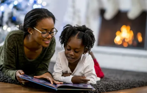 kid-parent-reading-books-under-Christmas-tree