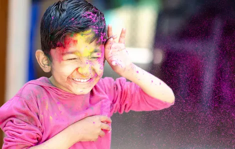Boy in colorful powder from Holi Festival