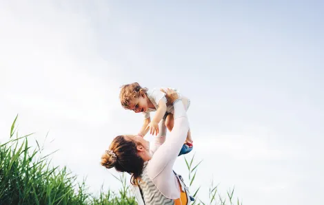 Women lifting smiling child into the air