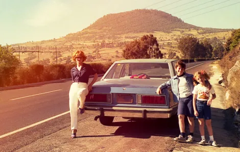 Vintage family photo standing by a car at the side of the road