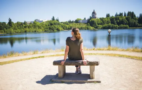 Woman sitting on a park bench relaxing and looking at water