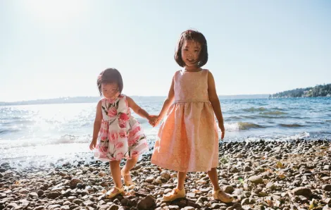 Two young girls holding hands on the beach