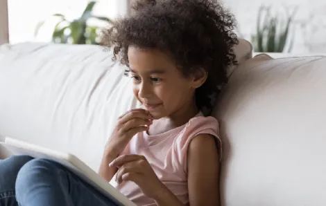 Kid-reading-a-tablet-on-sofa