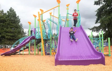 Child slides on a wide purple slide at the colorful new playground at Renton's Cascade Park