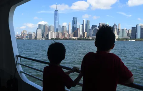 Two young children looking out from a ferry at the Manhattan skyline