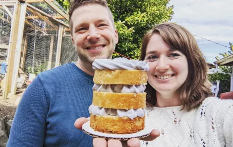 Man and woman smiling and holding a small three layer cake