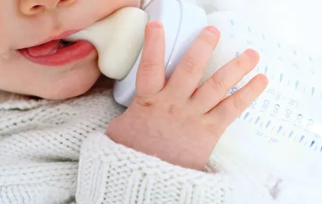 Close up of a baby with a bottle in their mouth