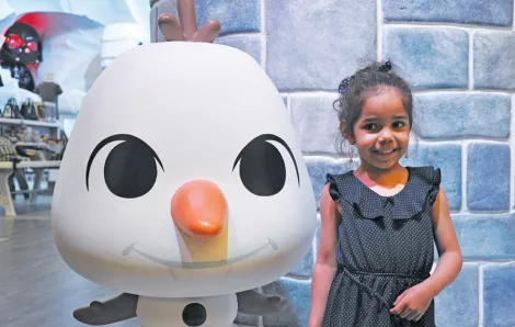 Young girl standing with Olaf Funko