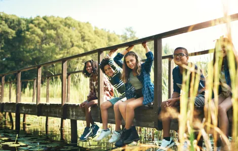 Group of tweens sitting on a dock by a lake in the summer
