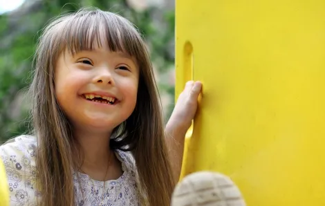 Young girl smiling on a slide.