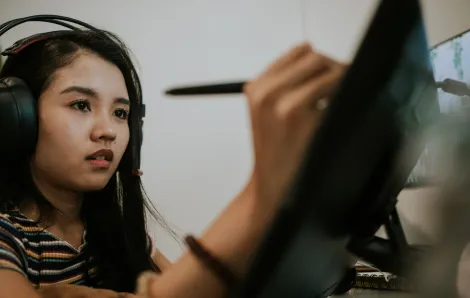 A young Asian woman uses a stylus to create animation on a computer screen