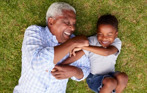 Grandpa and child lying in the grass laughing