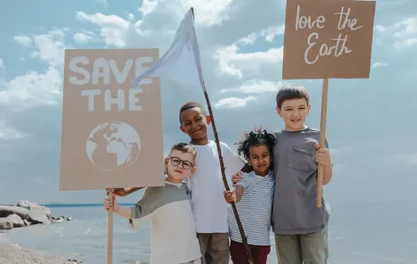 Three kids holding protest signs about protecting the environment