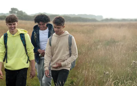 Three teenage boys walking in a field of grass 