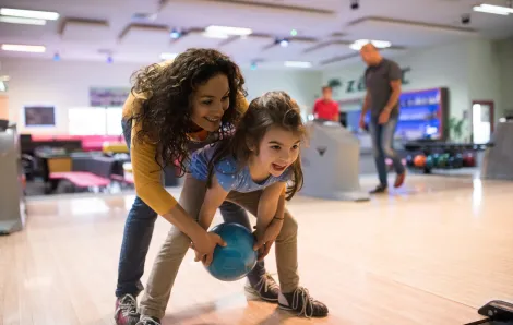Mother and daughter smiling while bowling at a Seattle bowling alley
