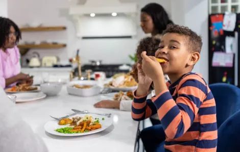 Child eating a Trader Joe's dinner idea with his family at a table