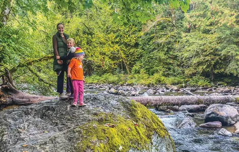 Mom and two children standing on a large rock next to a river at Twin Falls is a good winter hike near Seattle