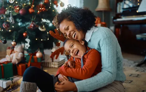 mom and kid laughing by a Christmas tree